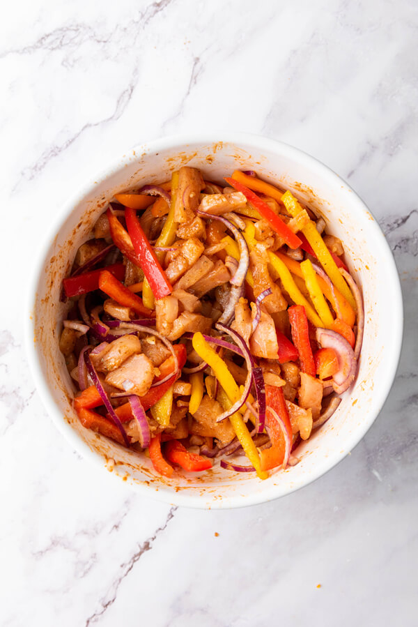 Mixing in minced garlic, sliced bell peppers, and red onion