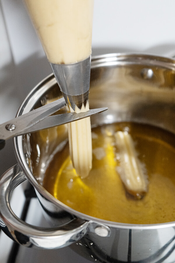 Pipping strips of dough into the oil