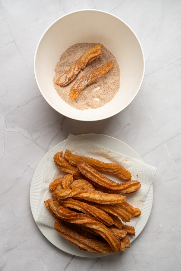 Tossing the churros in the cinnamon-sugar mixture