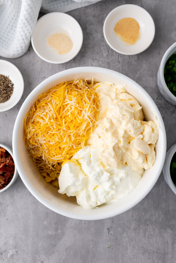 Combining corn, sour cream, mayonnaise, and Mexican cheese on a bowl