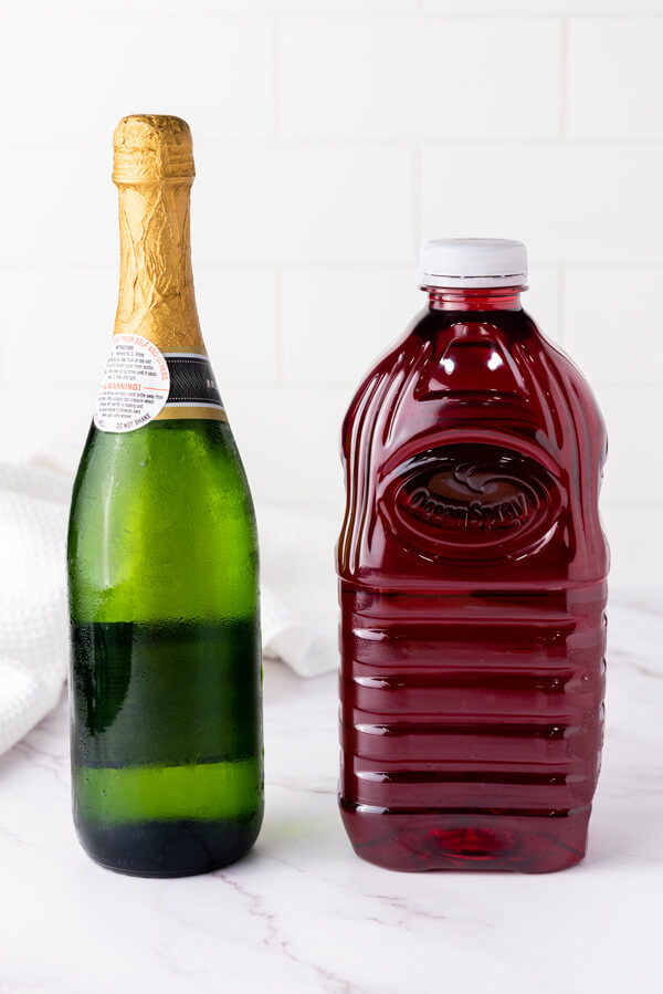 Bottle of champagne and bottle of cranberry juice on a kitchen counter top