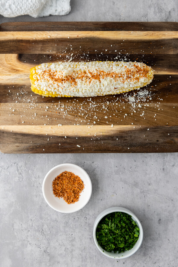 Covering corn with Cotija cheese and Tajin