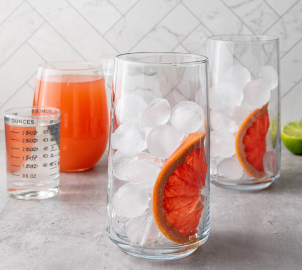 Two glasses filled with ice and a grapefruit slice