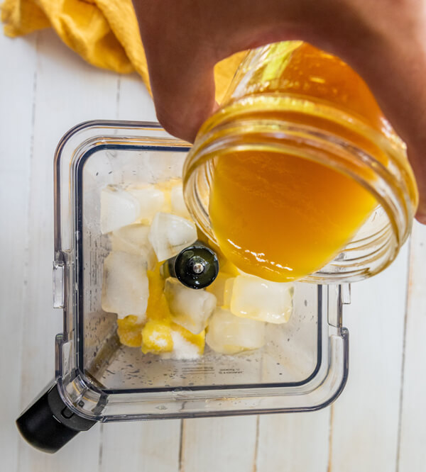 Adding frozen mango, mango nectar, ice, lime juice, and sugar into a blender