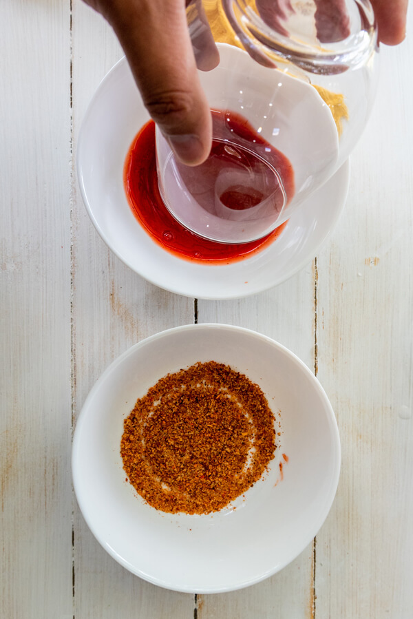 Dipping the rims of each glass in chamoy sauce and tajin