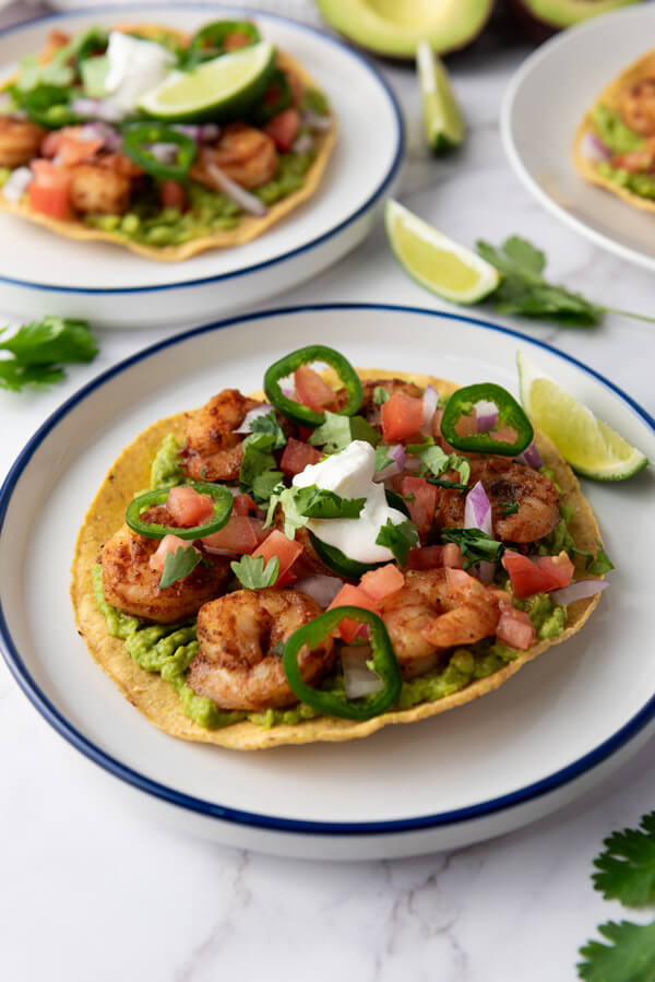 Serving shrimp tostadas with cilantro and lime wedges