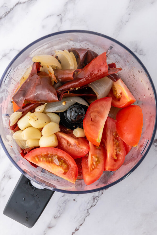 Blending tomatoes, guajillo chilies, onion, garlic (peeled), and broth