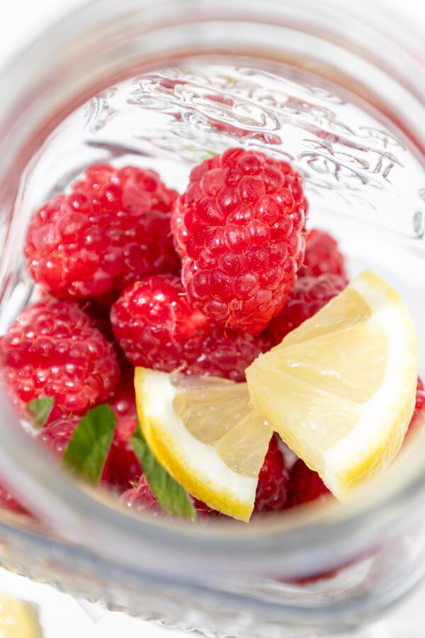 Combining raspberries, mint leaves, and lemon slices