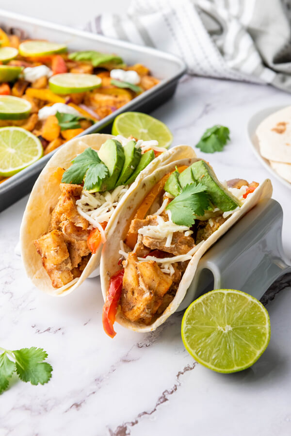 Serving chicken fajitas on a tortilla with fresh lime juice, diced avocado, sour cream, shredded mozzarella