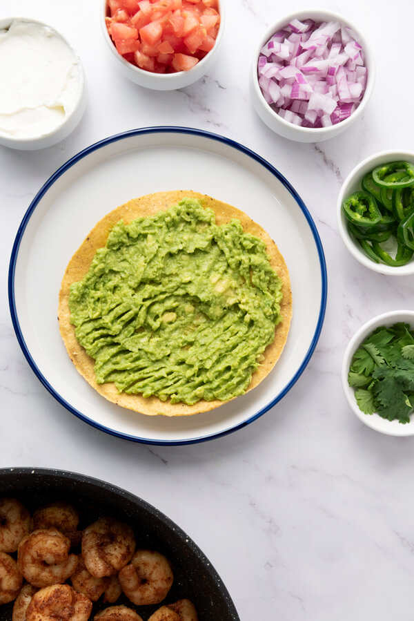 Spreading the avocado cream on a tostada shell