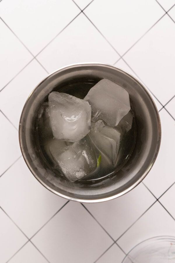 Combining tequila, triple sec, lime juice, agave syrup, jalapeño slices, and ice cubes