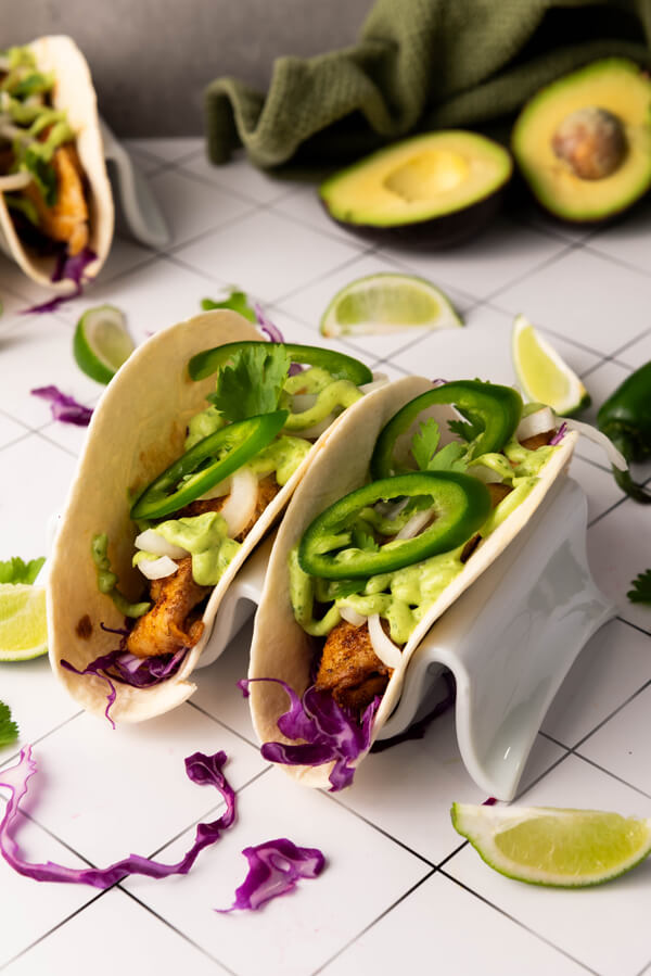 Tilapia fish tacos served with avocado cilantro sauce, jalapenos, and a lemon