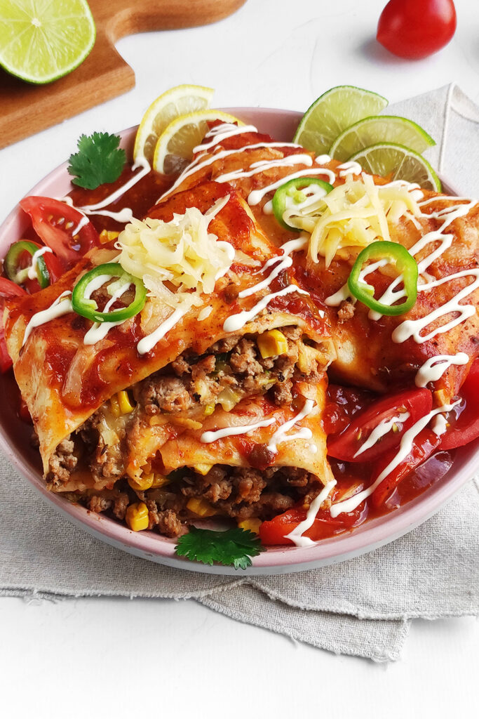 Wet Burritos served with sour cream, fresh tomatoes, more cilantro, and lime wedges