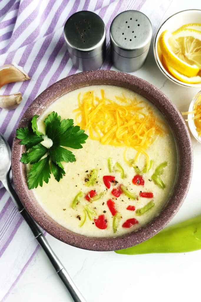 Serving corn chowder with shredded cheese, crushed red pepper flakes, jalapeno slices, parsley and lemon slices