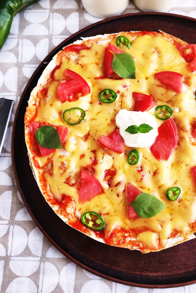 Serving Mexican Pizza with melted cheese and sour cream