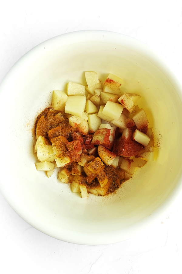 Mixing potatoes with salt, pepper, smoked paprika, and taco seasoning