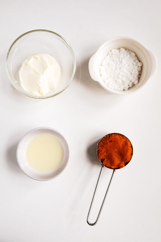 With table with bowls filled with cream cheese, powdered sugar, milk, and pumpkin puree