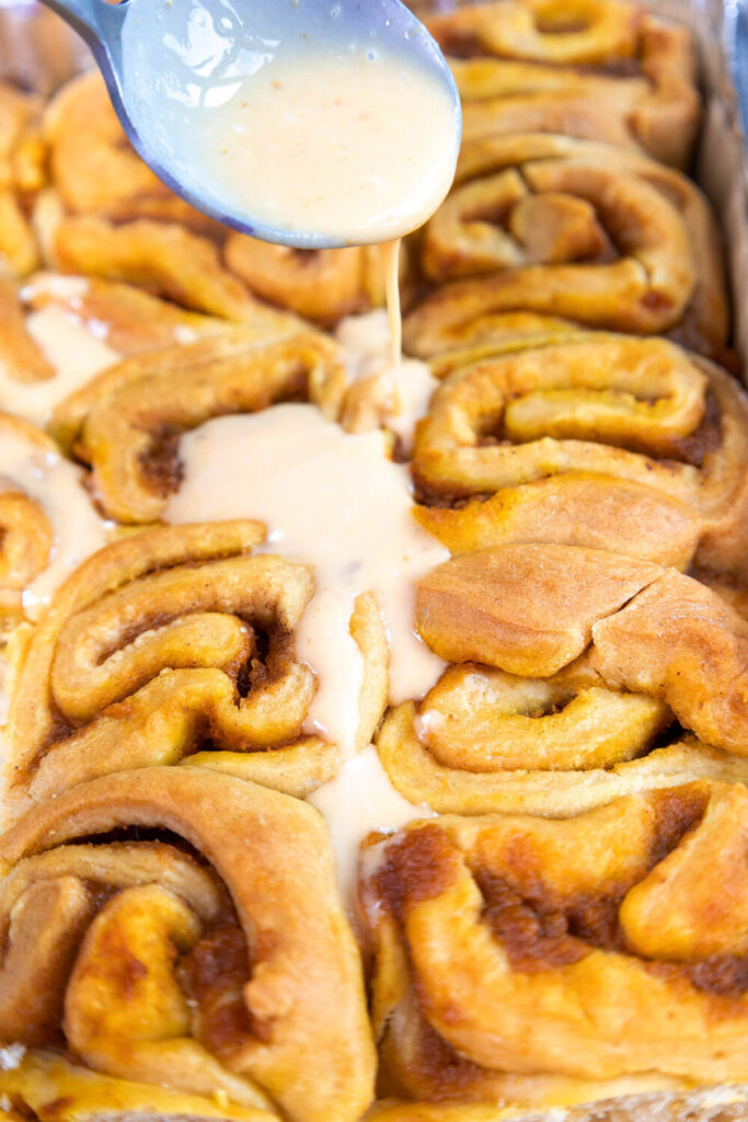 Spreading the frosting on the cinnamon rolls