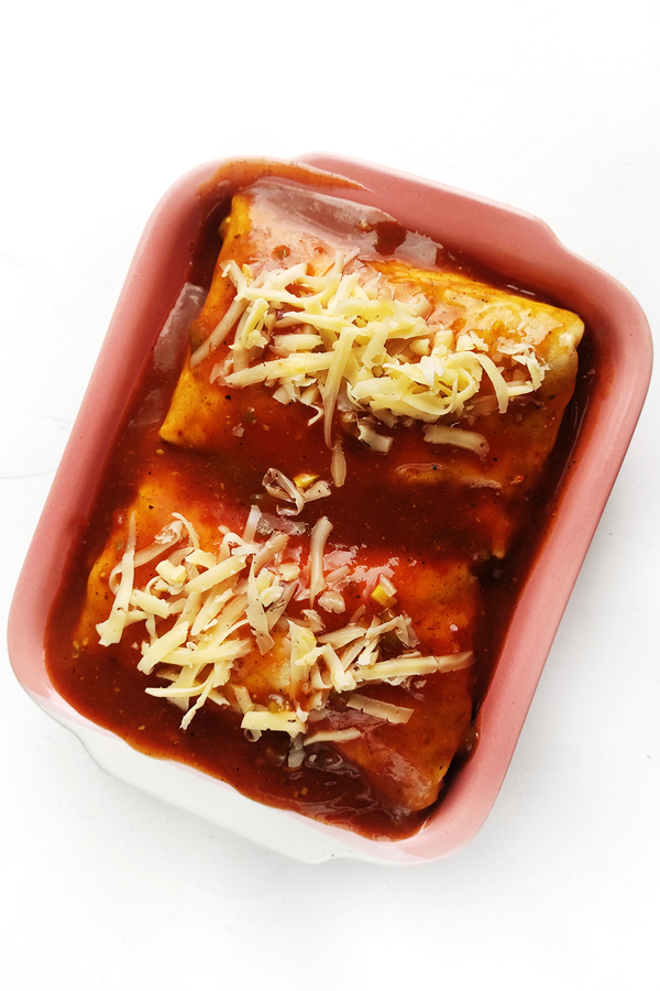 Adding burritos and covering with sauce and cheese