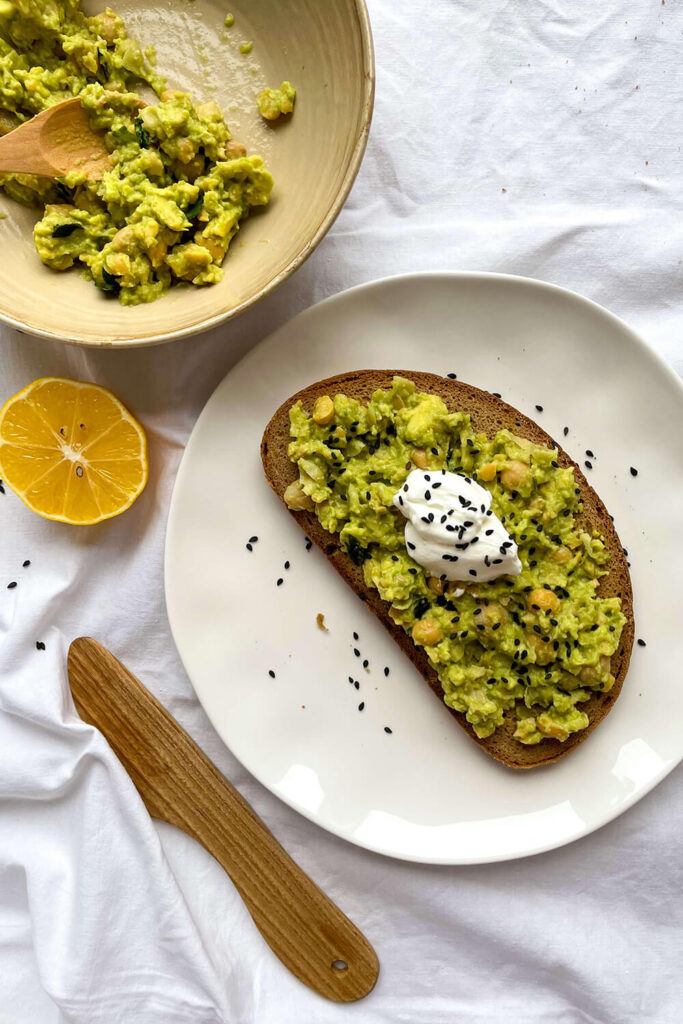 Serving avocado chickpea toast with a dollop of Greek yogurt and parsley