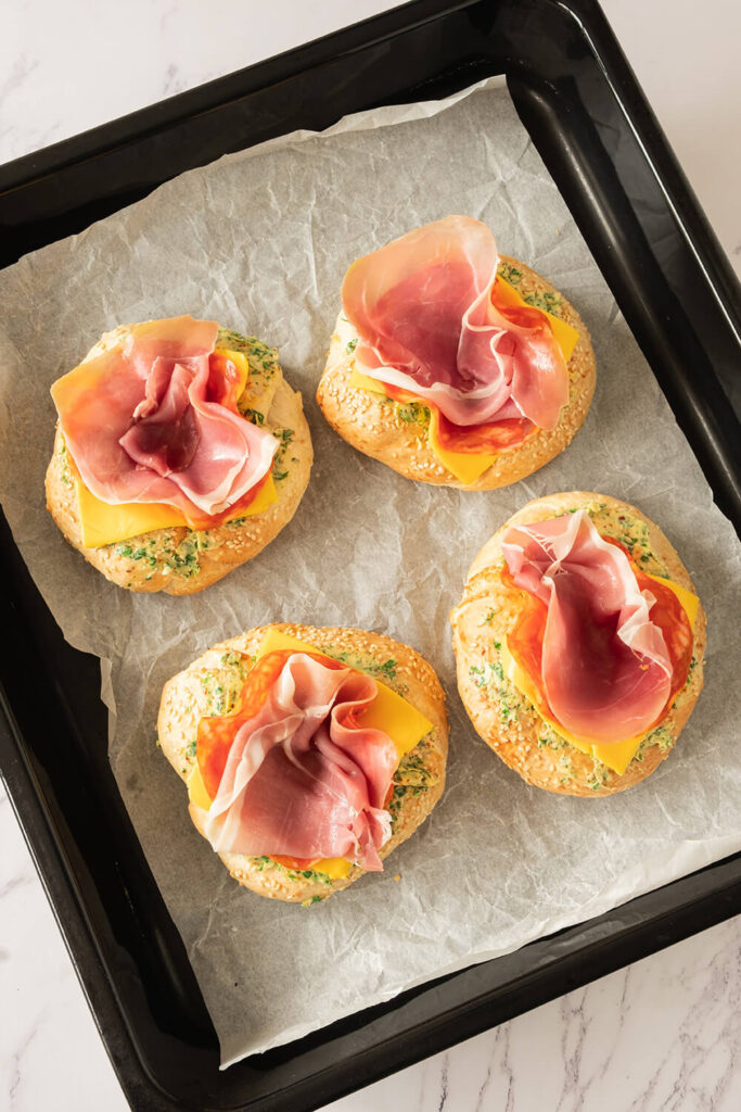 Pushing salami and prosciutto into the center of the bagel.