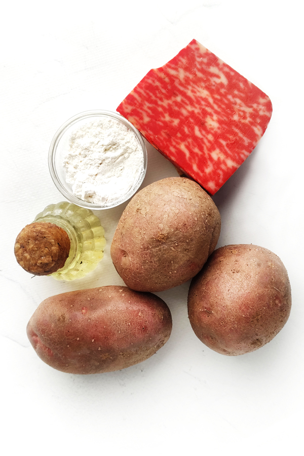 White table with red cheese, potatoes, olive oil, and flour