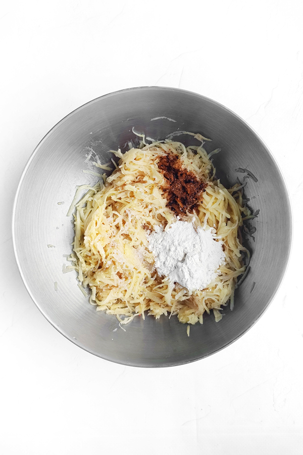 Mixing grated potatoes, paprika, salt, pepper, and flour