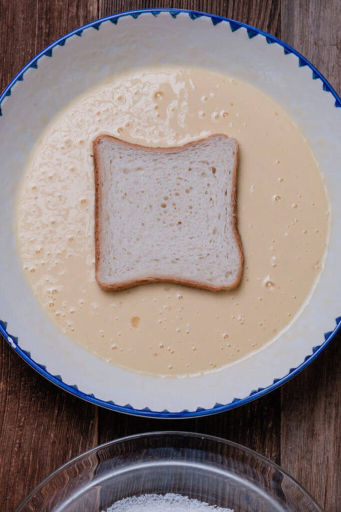 Dipping each slice of bread into the egg mixture