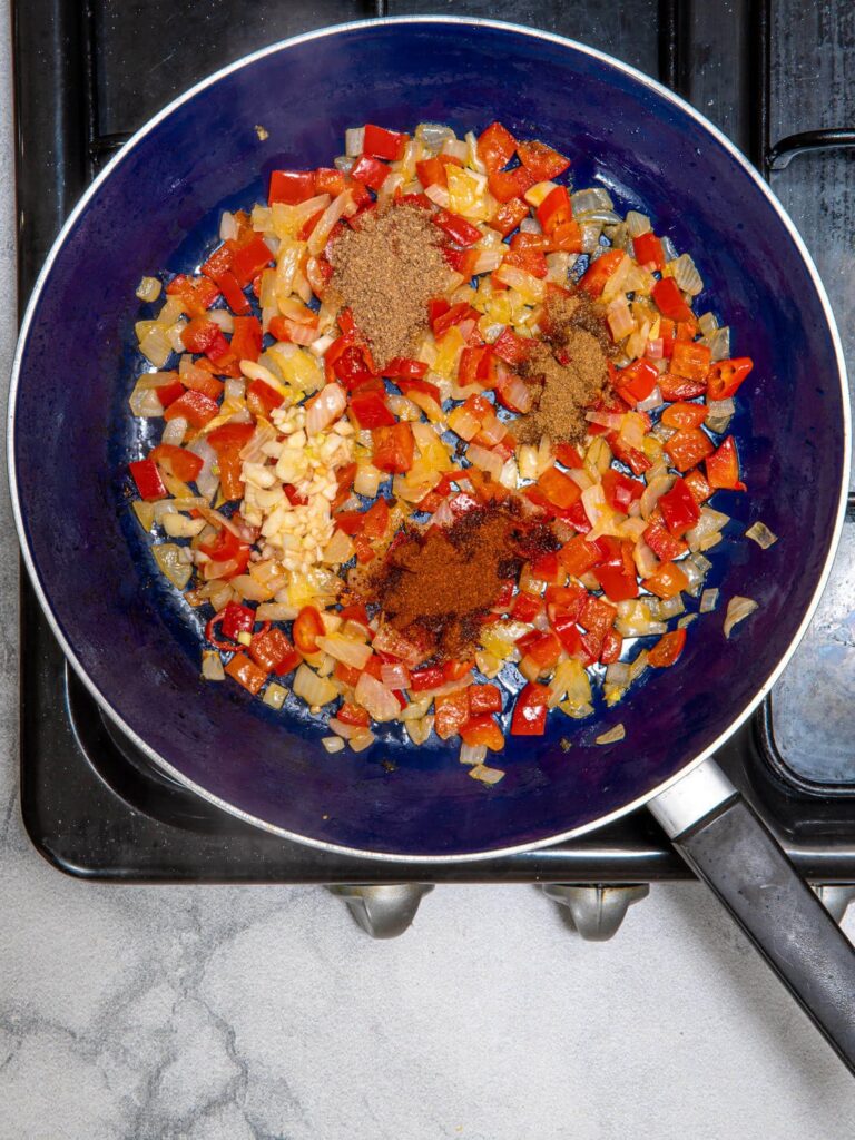 Adding garlic, cumin, coriander, and smoked paprika