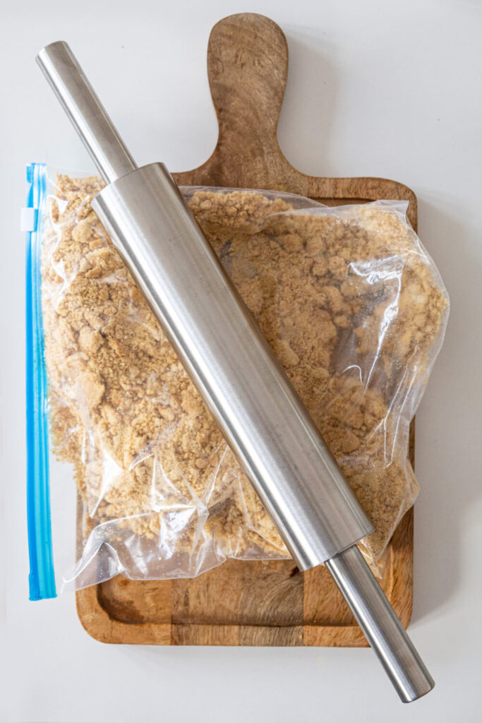 Crushing the cookies inside a plastic bag with a rolling pin