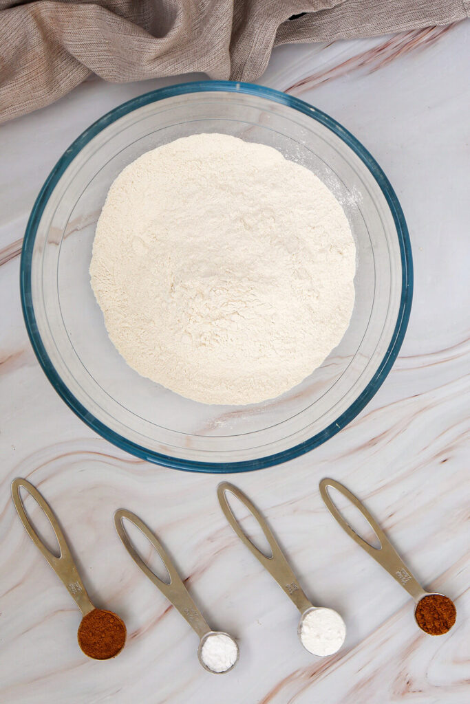 Mixing  flour, baking powder, baking soda, cinnamon, and allspice 
