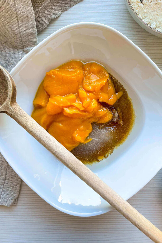Combining  pumpkin puree, white sugar, brown sugar, and melted coconut oil with the flax mixture