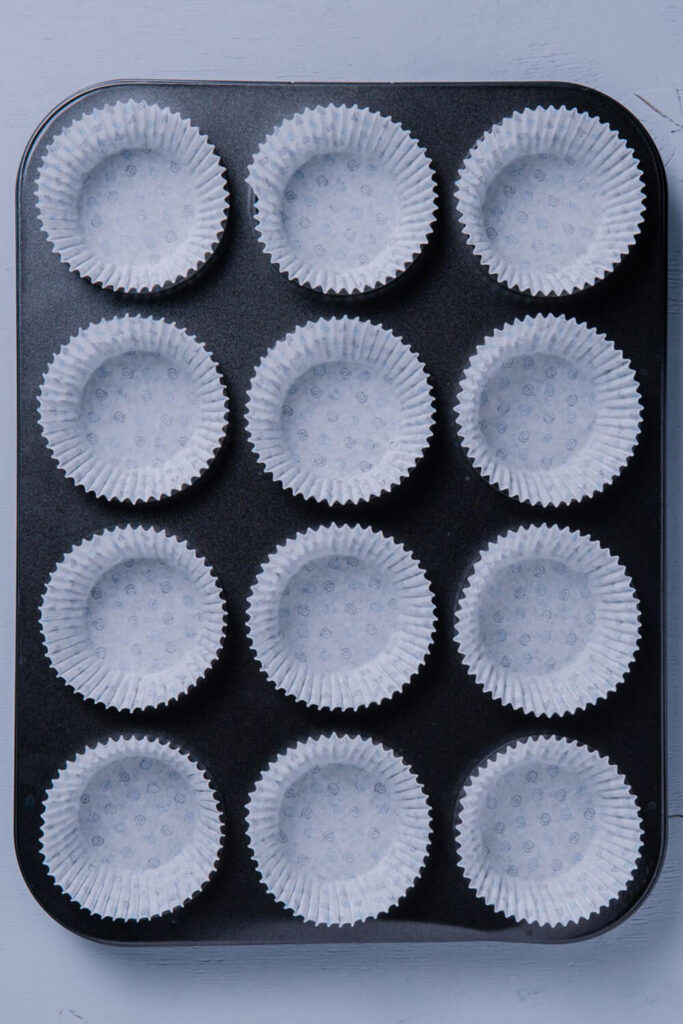 Lining a 12-cup muffin tin with paper liners