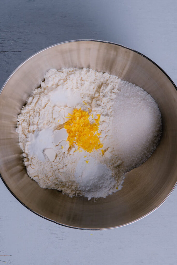 Mixing flour, salt, baking powder, baking soda, sugar, and lemon zest