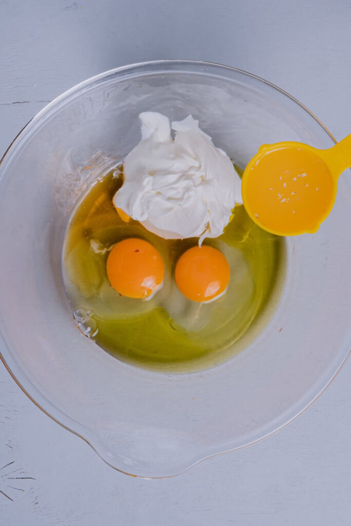 Mixing the eggs, oil, yogurt, lemon juice, and honey