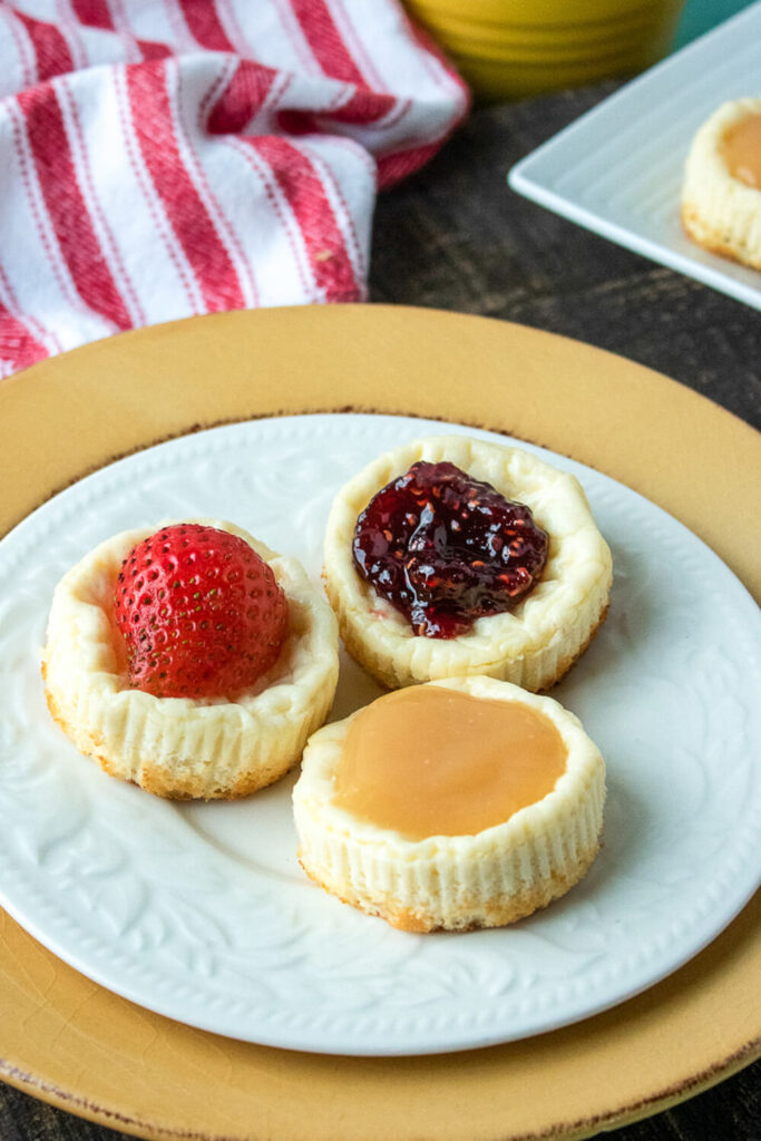 Serving the mini cheesecakes with lemon curd, raspberry jam, and fresh strawberries