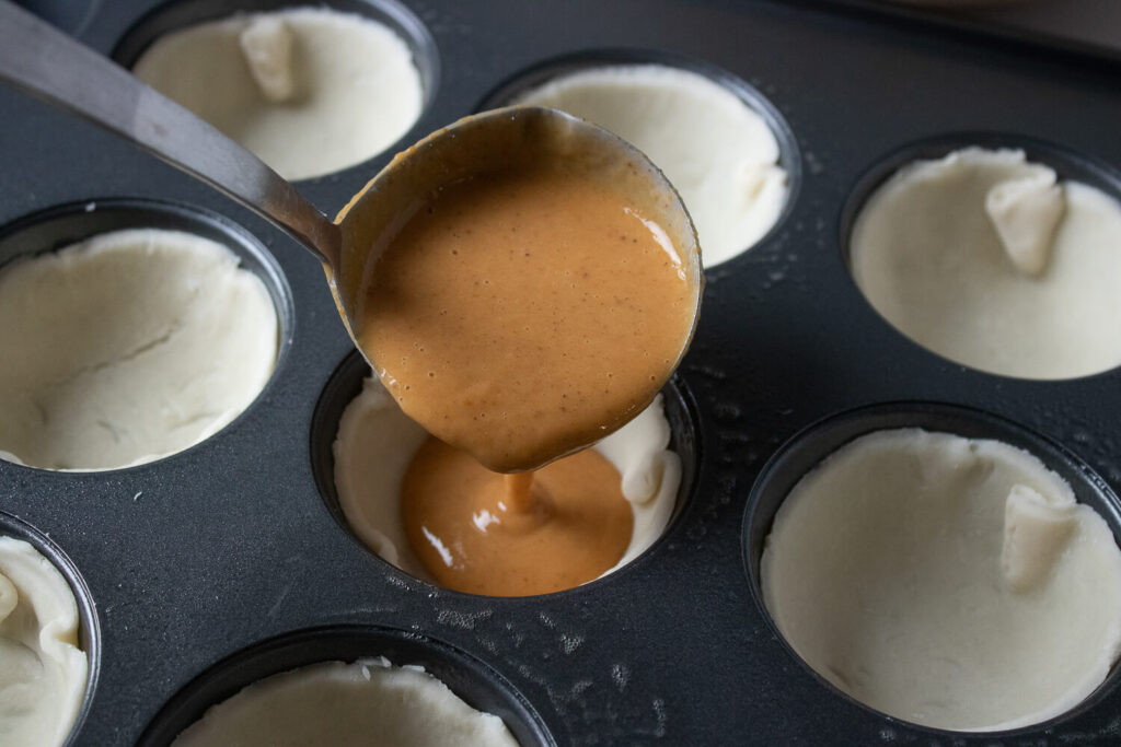 Dividing the filling evenly among the mini pie crust
