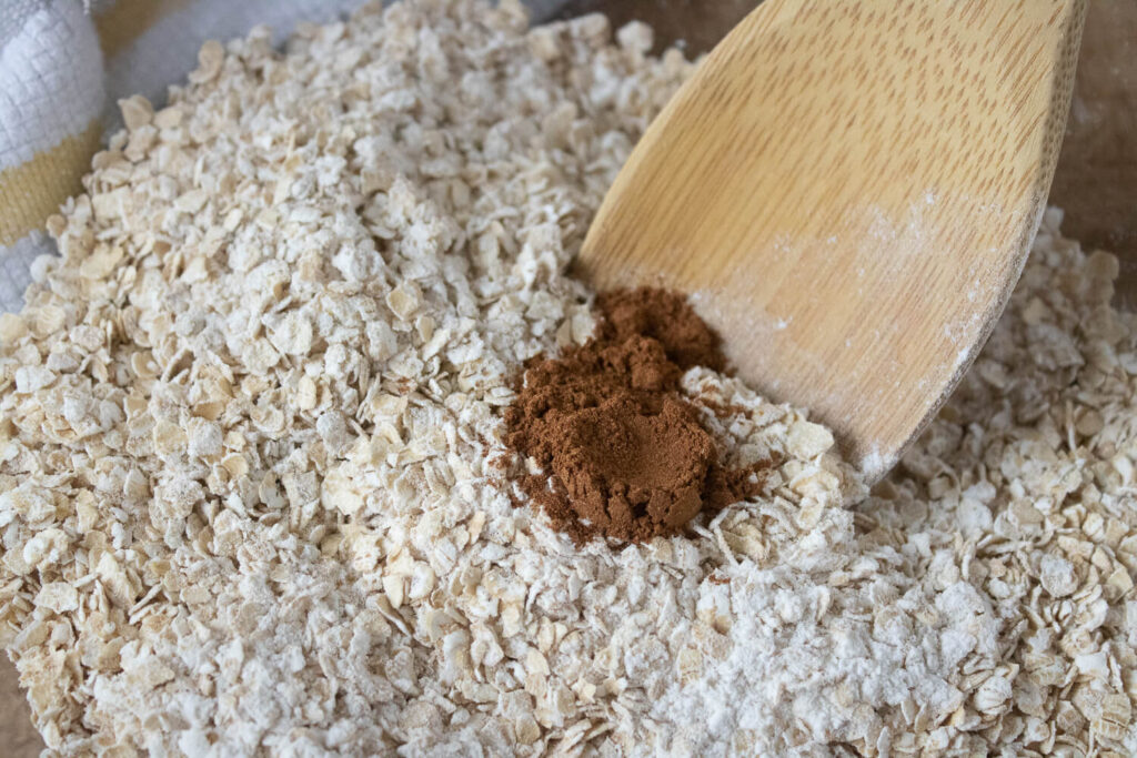 Mixing quick oats, flour, pumpkin pie spice, baking powder, baking soda, and salt