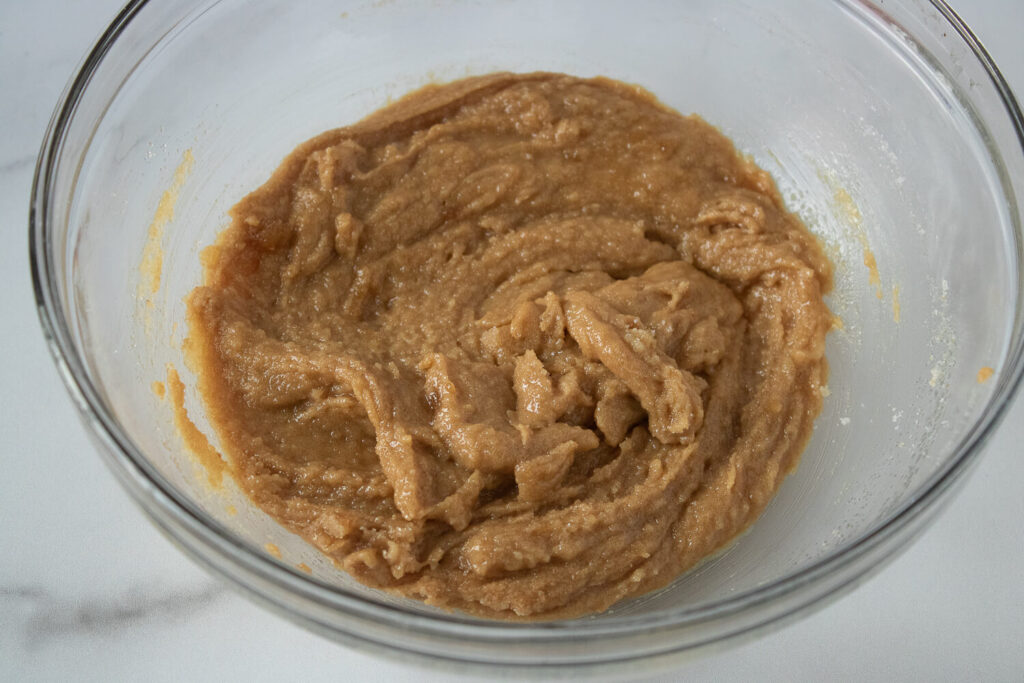 Mixing peanut butter, melted butter, granulated sugar, brown sugar, egg, and vanilla extract