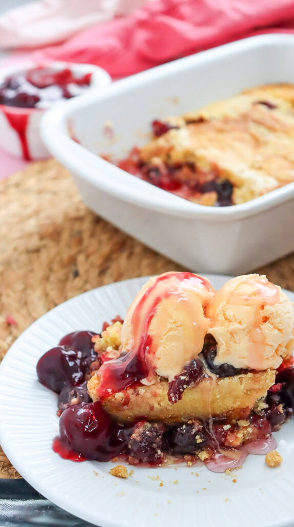 Serving the cherry dump cake with a scoop of ice cream