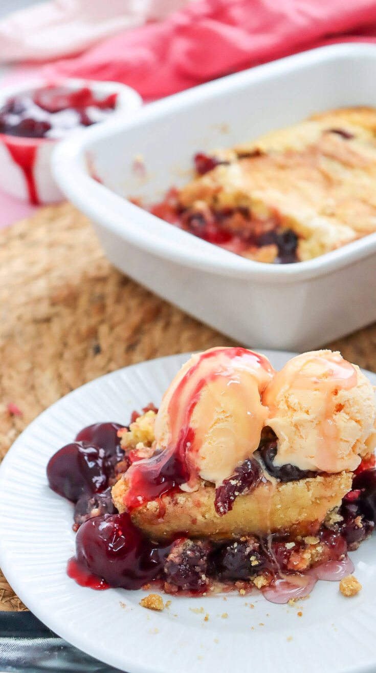 Serving the cherry dump cake with a scoop of ice cream