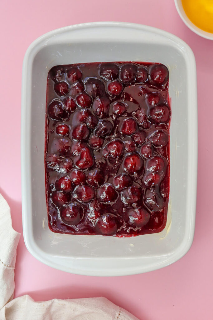 Spreading cherry pie filling on a baking dish